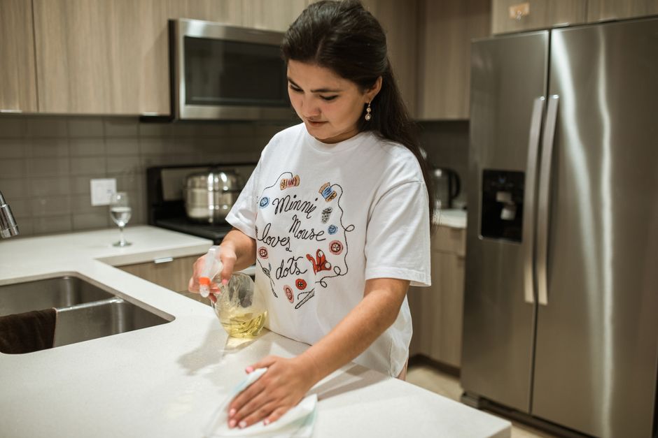 Professional wiping a kitchen counter during a recurring cleaning visit